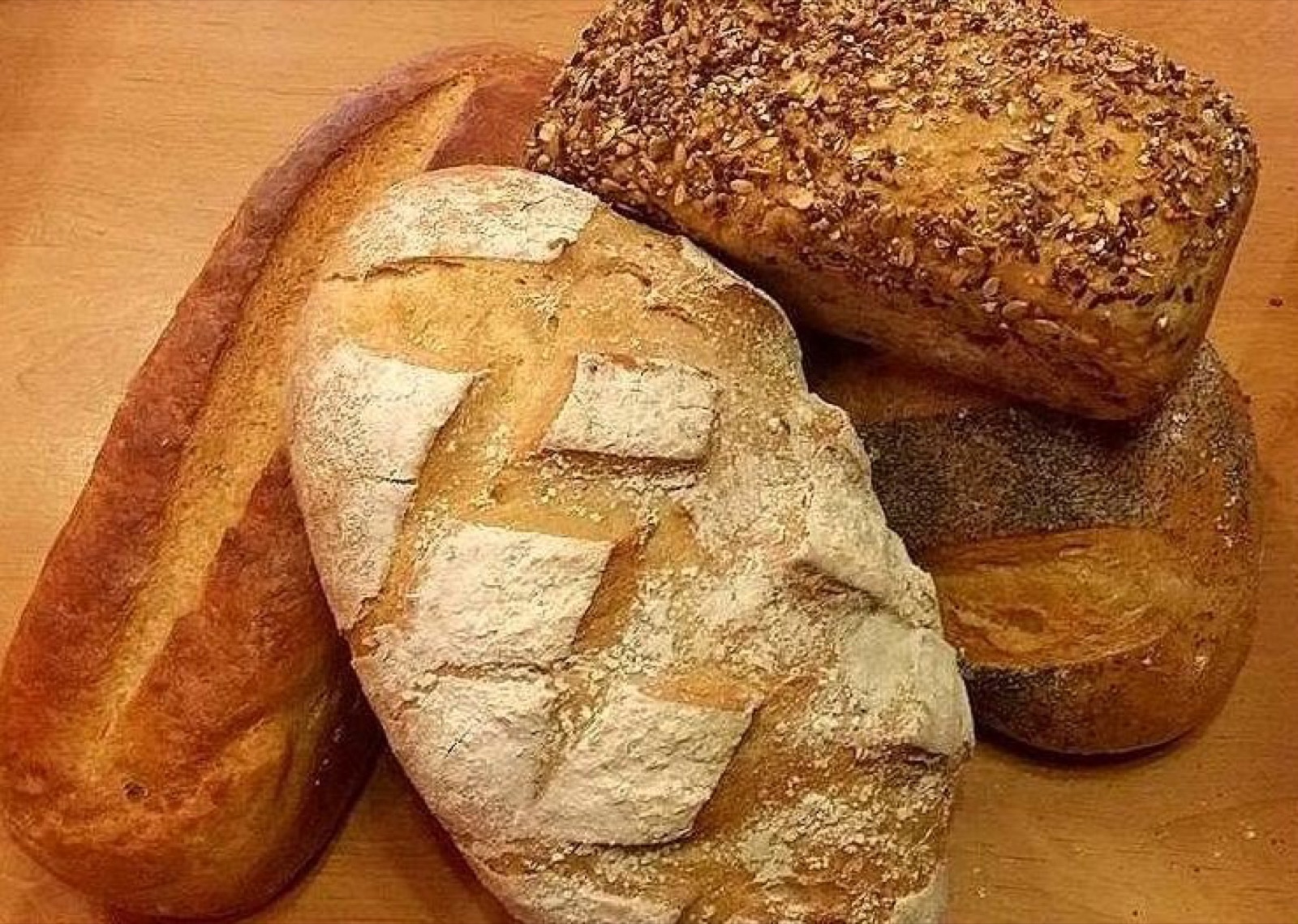 Bochenki chleba: pszenny, razowy z ziarnami i wiejski.